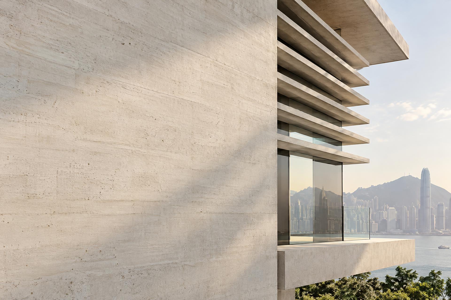 Modern minimal building façade in Hong Kong: pale concrete fins, a frameless glass insertion and a cantilevered slab edge in soft morning light